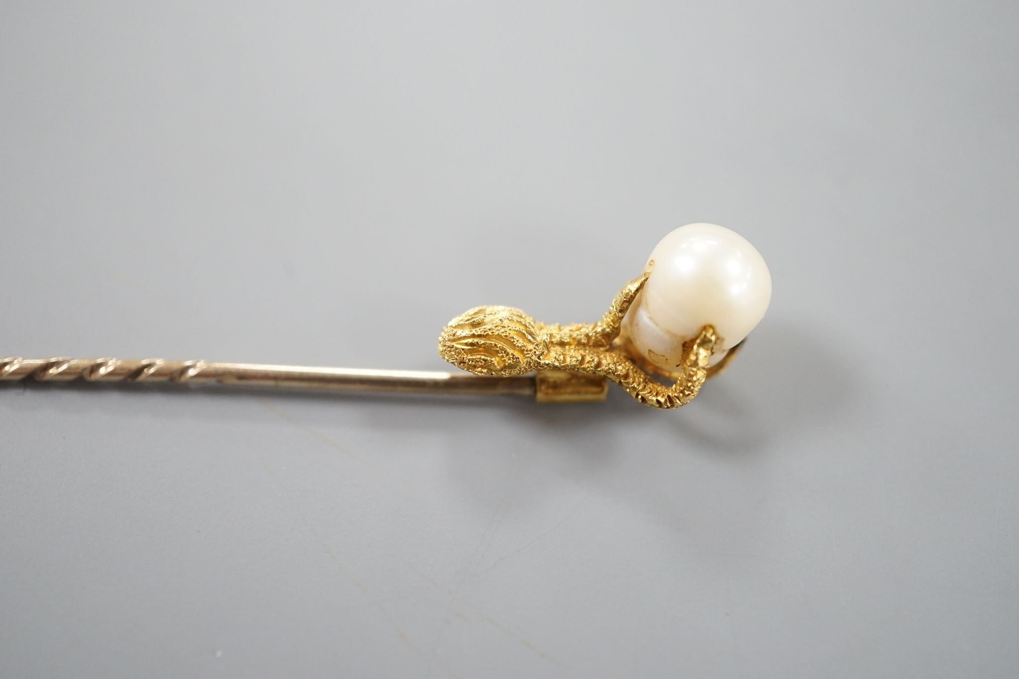 A 19th century yellow metal stick pin, the terminal modelled as an eagle's claw grasping a baroque pearl, 78mm, gross weight 3.3 grams, with box.